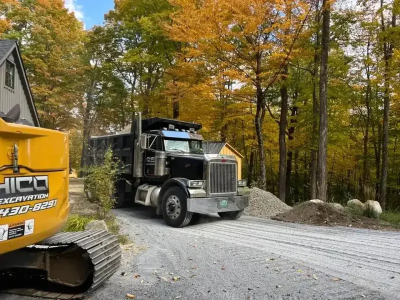 Chico Excavating excavator and dump truck on a gravel driveway