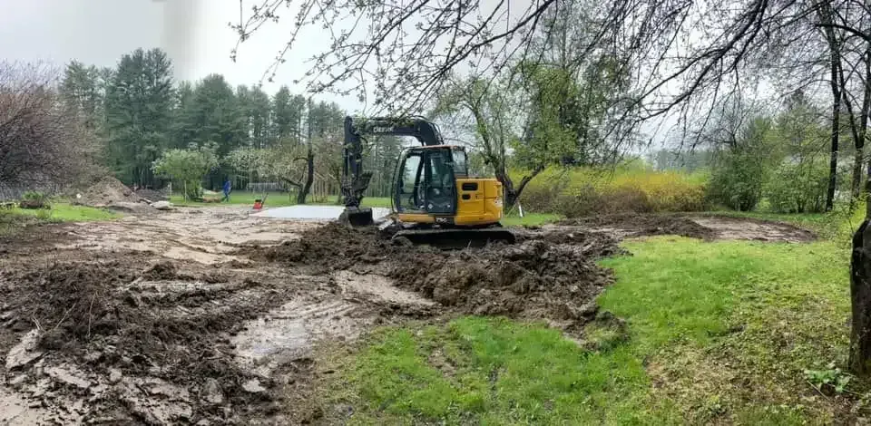 John Deere excavator regrading a muddy yard